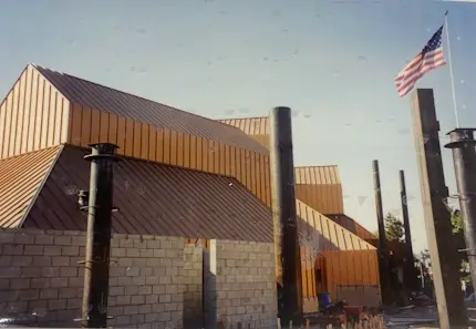 A small building with a tall brown metal roof that is under contruction.