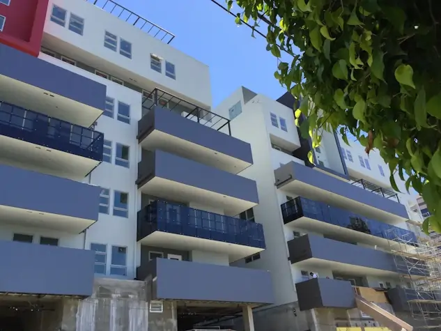 A small white and metallic silver apartment building with a green accent color.