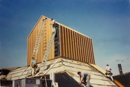 A team of contruction workers intalling parts onto a metal roof.