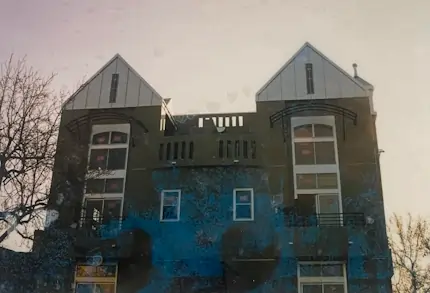 A gray multi story bulding with a silver metal roof.