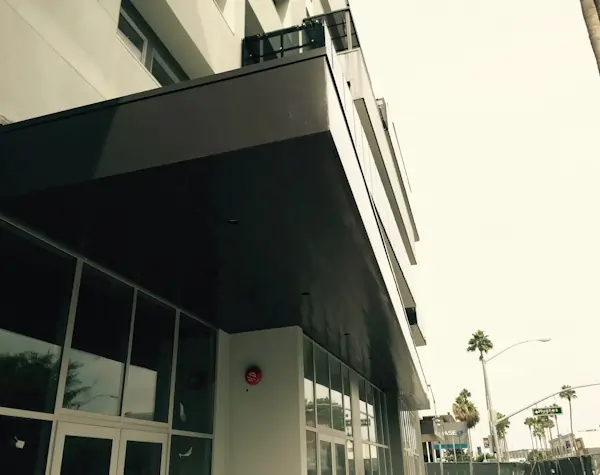A gray metal overhang at the enterance of a buuilding.