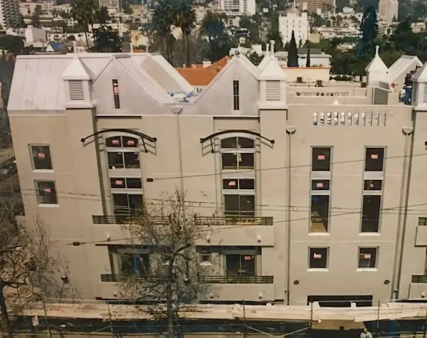 A large beige apartment complex with a detailed white metal roof.