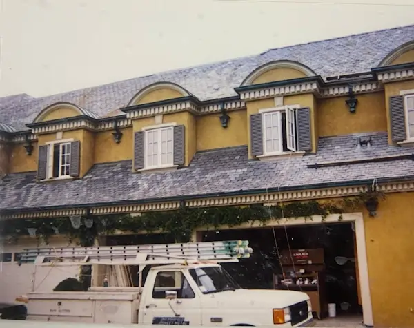 An old style yellow house with a metal roof that is under construction.